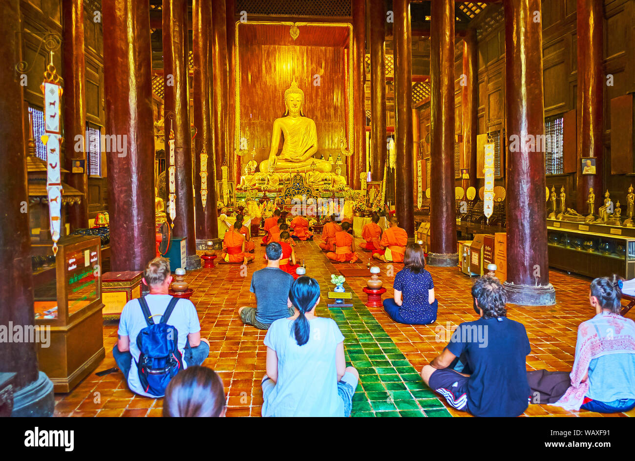 CHIANG MAI, THAILAND - 2. Mai 2019: Die Anbetung in der mittelalterlichen teak Wat Phan Tao Tempel; bhikkhu Mönche sitzen vor dem Altar und dem buddhistischen Anhänger Stockfoto