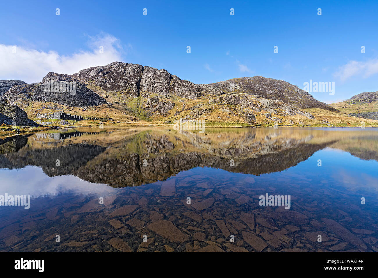 Llyn (See) Cwmorthin zeigen alte Cottages des stillgelegten Schiefergrube mit Schiefer Abfälle auf dem See Bett in der Nähe von Blaenau Festiniog North Wales UK April 2018 Stockfoto