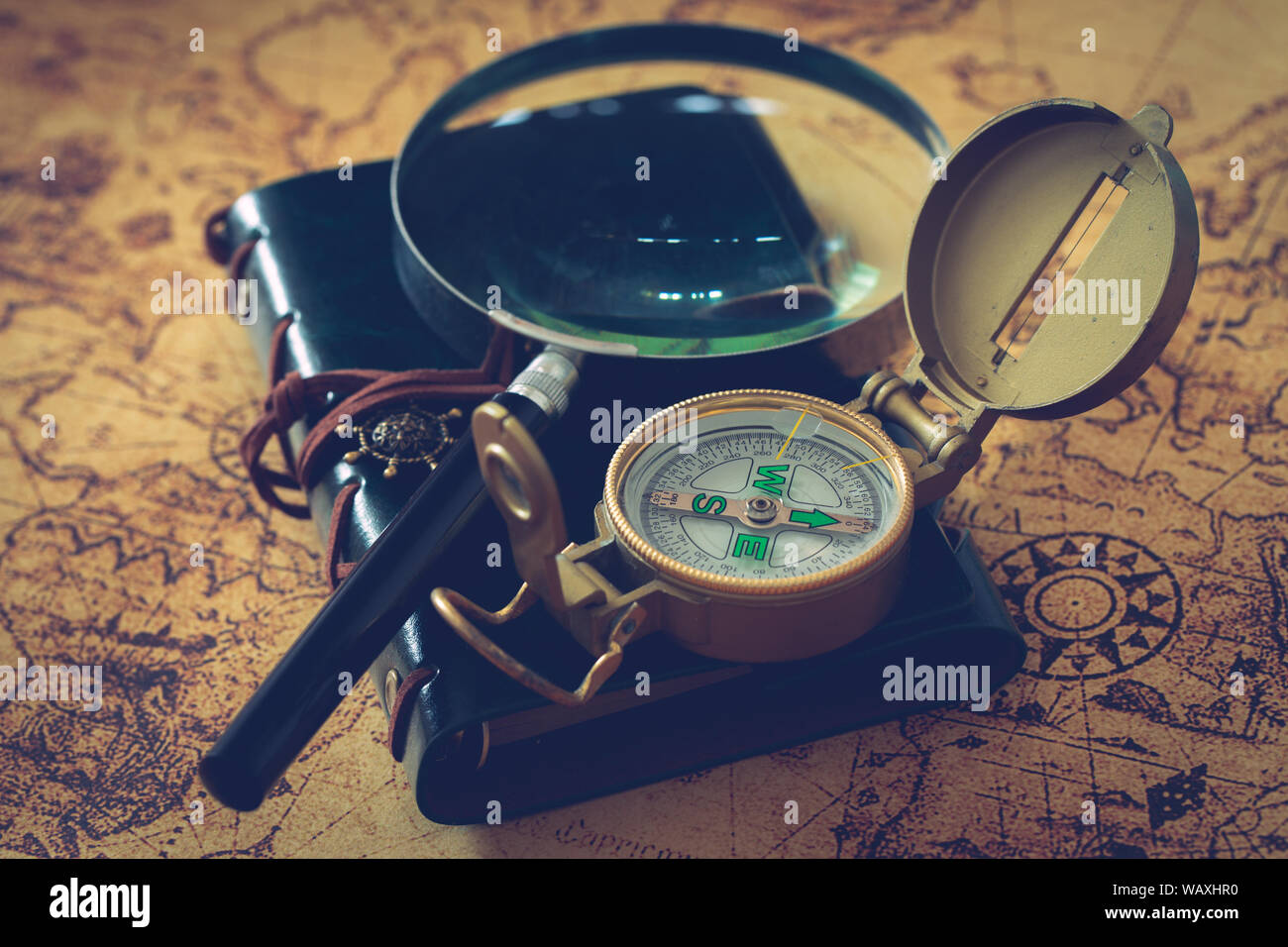 Alte Karte mit Kompass, Notebook und Lupe. Das Konzept der Suche nach interessanten Orten oder Schätze auf der ganzen Welt. Stockfoto