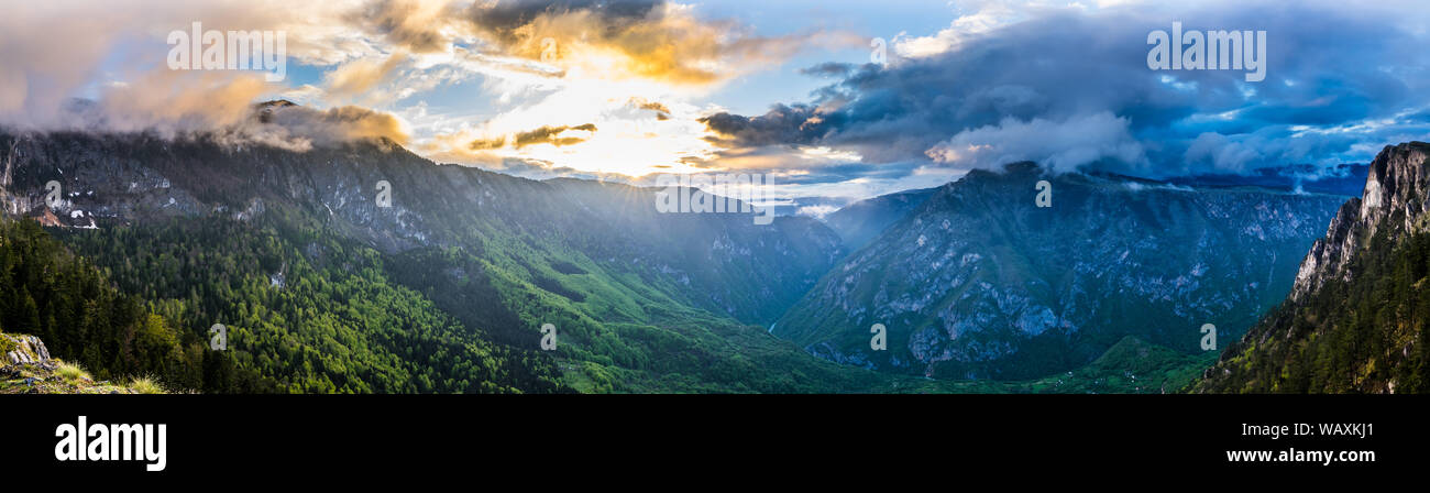 Montenegro, XXL Panorama von orange Sonnenuntergang Himmel und Wolken in Licht über Welt berühmten Fluss Tara Canyon Natur Landschaft vom Gipfel des Cu montieren Stockfoto