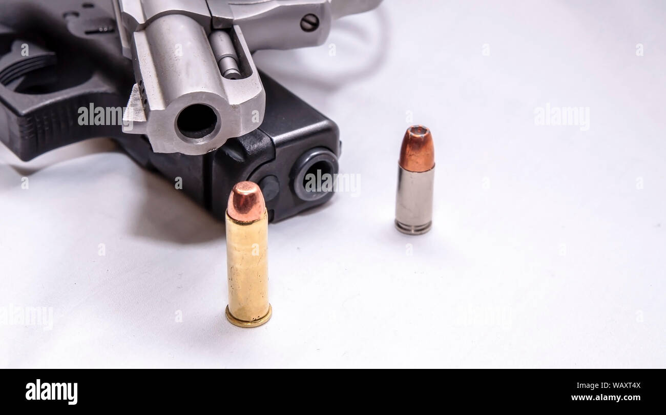 Eine Brüskierung gerochen, Edelstahl 357 Magnum Revolver auf einem schwarzen 9 mm Pistole mit einer Gewehrkugel für jedes Kaliber vor Ihnen auf weißem Hintergrund Stockfoto