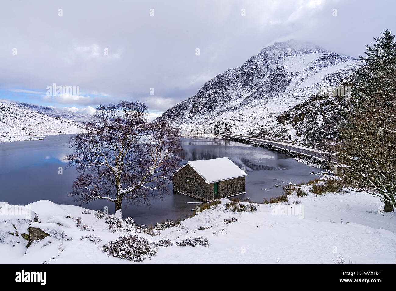 Llyn Ogwen im Winter nach Osten zeigt das Bootshaus mit der A5 Road und Tryfan Berg auf der rechten Snowdonia National Park North Wales UK Februar 2018 Stockfoto