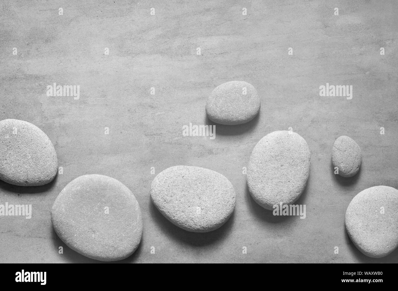 Flach Zusammensetzung mit grauen spa Steine auf grauem Hintergrund. Stockfoto