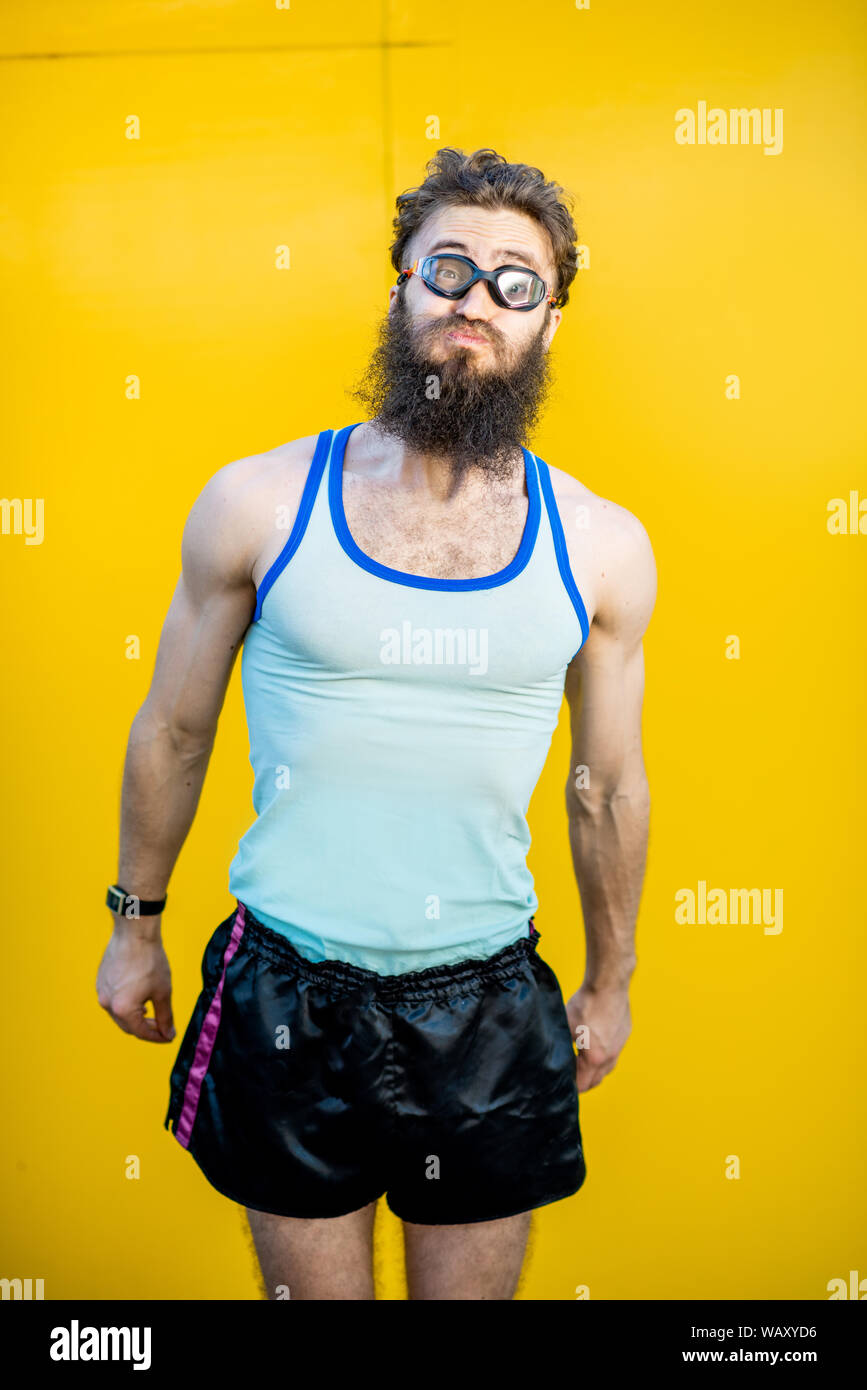 Porträt einer sonderbaren, altmodische Schwimmer im 80er Jahre Stil mit Schwimmbad Gläser auf dem gelben Hintergrund Stockfoto