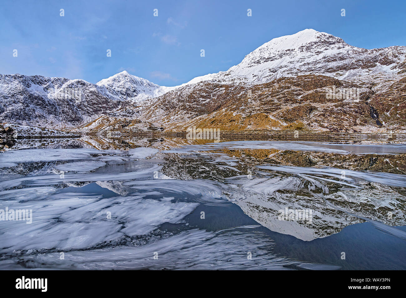 Krippe Goch Berge und den Mount Snowdon in Llyn Llydaw mit Eis auf der Wasseroberfläche Snowdonia National Park North Wales UK März 2018 wider Stockfoto