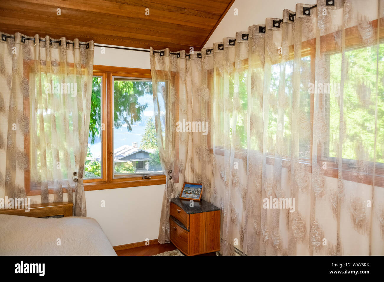 Große Fenster und Vorhänge in kleinen Schlafzimmer mit Meerblick und Blick auf die Bucht. Stockfoto