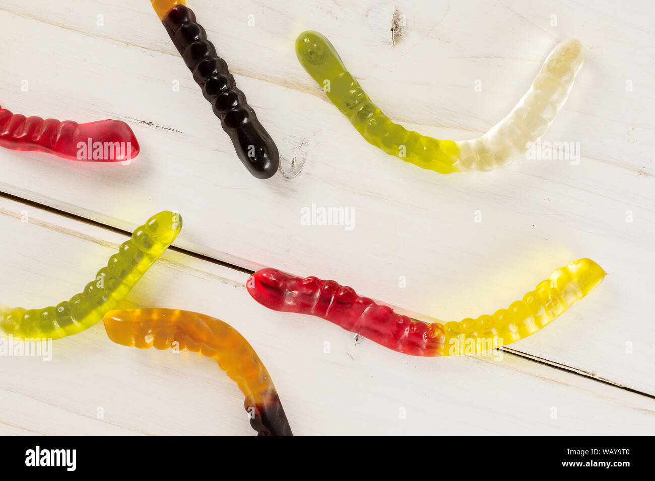 Gruppe von sechs ganze Bunte Jelly Wurm candy flatlay auf weißem Holz Stockfoto