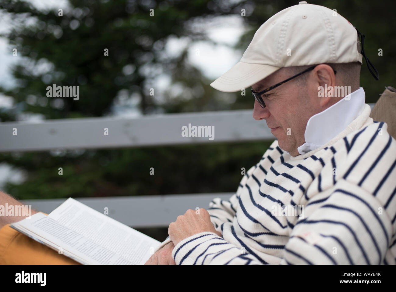 Mid-Adult Mann Lesebuch auf Deck Stockfoto