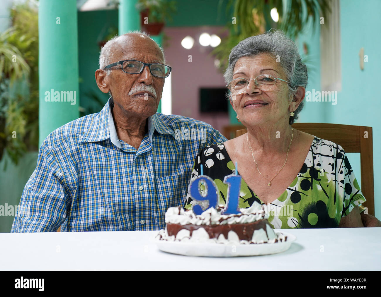 Ältere Paare mit einem Kuchen auf dem Tisch und die Nummer 91 auf dem Kuchen Stockfoto