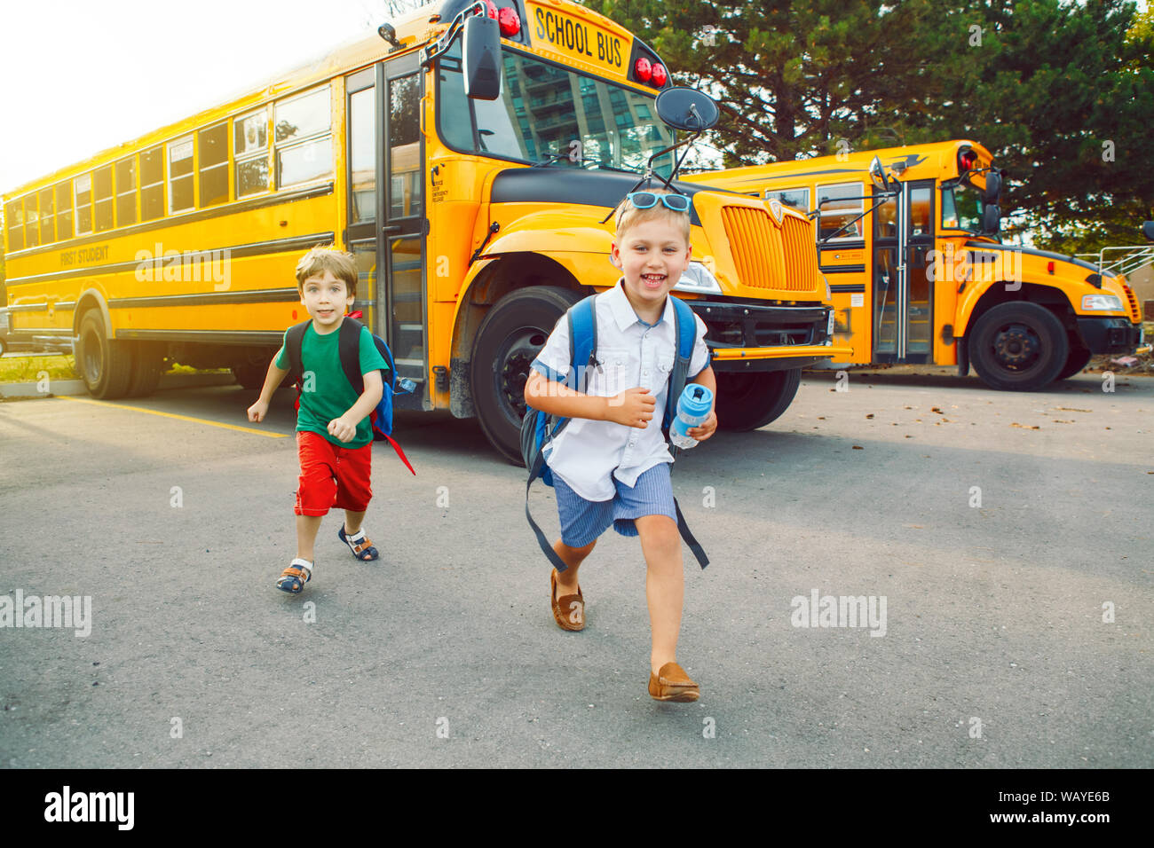 Zwei lustige glücklich Kaukasischen jungen Schüler Kinder laufen in der Nähe von Yellow Bus am 1. September. Bildung und zurück in die Schule. Kinder Freunde Schüler Stockfoto