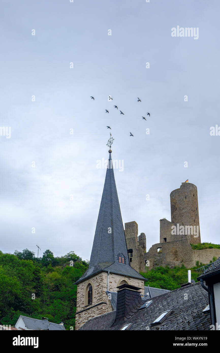 Pfarrkirche Kirche und Löwenburg schloss mit fliegenden Vögel im Hintergrund an der malerischen Ortschaft Monreal in der Eifel, Deutschland Stockfoto