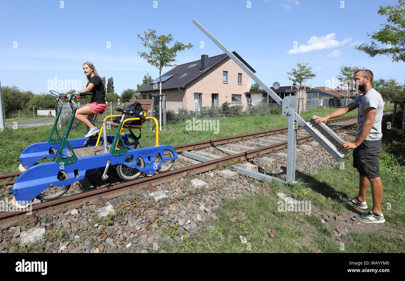 20. August 2019, Mecklenburg-Vorpommern, Waren (Müritz): Urlauber reisen mit dem Trolley zwischen den ehemaligen Güterbahnhof und die Mecklenburgische Schweiz Natur Park und eine Barriere muss vor dem Überqueren einer Straße geöffnet werden. Die Route der "raisine Mecklenburg" zwischen Waren (Müritz) und Schwinkendorf ist 13 Kilometer lang, kürzere Touren sind natürlich auch möglich. Wer will zu überholen die Katze mit seiner Front Mann austauschen müssen. Foto: Bernd Wüstneck/dpa-Zentralbild/ZB Stockfoto