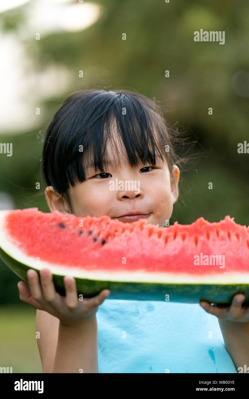 Glückliche kleine Mädchen mit Wassermelone in einem Garten Stockfoto