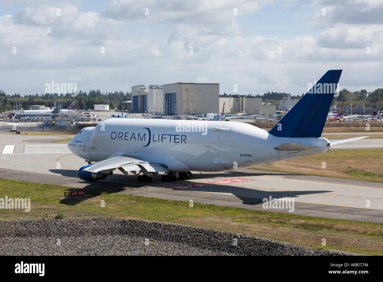 Eine Dreamlifter Taxis in die Position für den Start bei Paine Field in Everett, Washington am 22. August 2019. Die wide-body Cargo Aircraft ist eine modifizierte Boeing 747-400 zum Transport Komponenten der Boeing 787 Dreamliner. In der Ferne sind die Boeing Everett Farbe hangars, wo eine Mehrheit von Boeing wide-body Flugzeuge vor der endgültigen Flight Test bemalt sind. Stockfoto