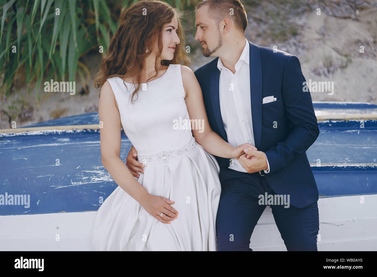 Schönen jungen langhaarigen Braut im weißen Kleid mit ihr junger Ehemann am Strand Stockfoto