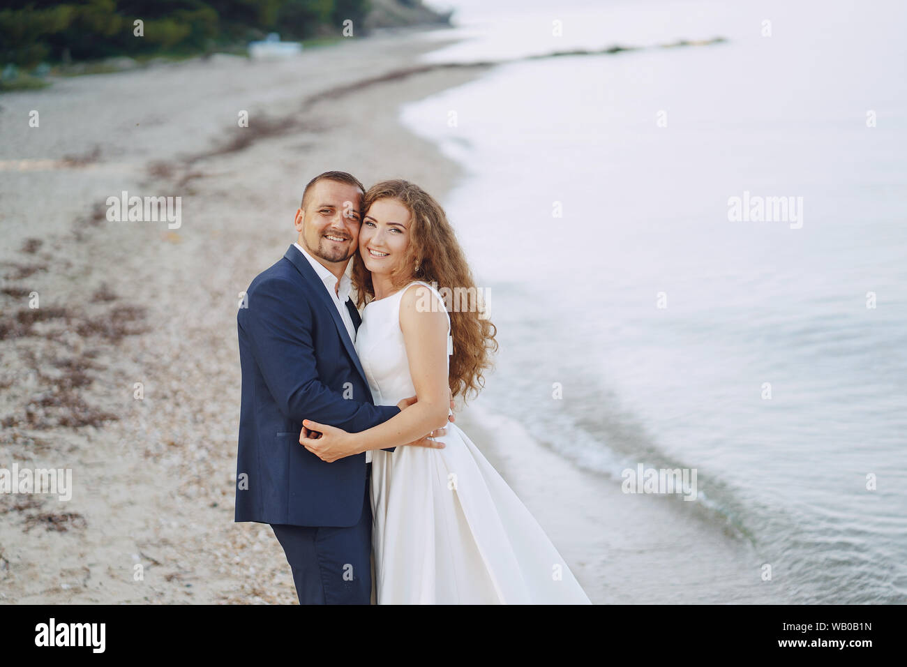 Schönen jungen langhaarigen Braut im weißen Kleid mit ihr junger Ehemann am Strand Stockfoto
