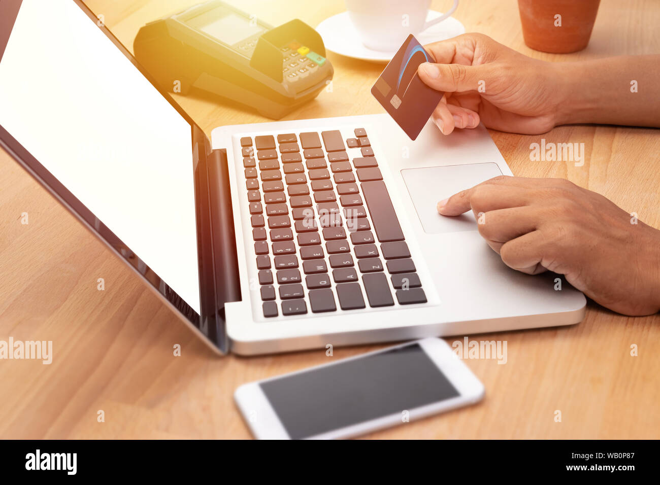 Mann hält eine Kreditkarte und Kauf online Zahlung per Computer Notebook Laptop mit leeren weißen Bildschirm am Arbeitsplatz Stockfoto