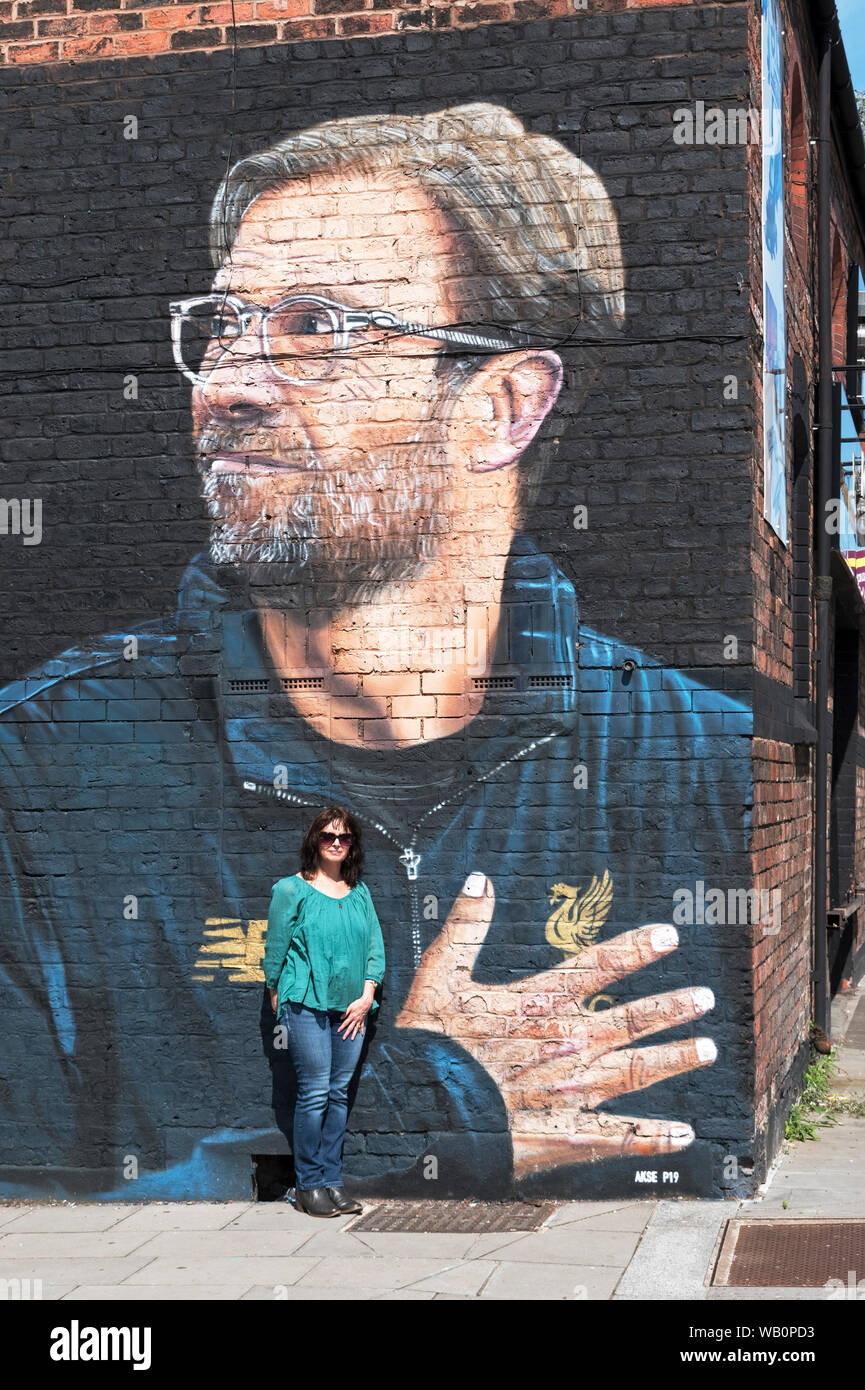 Weibliche Liverpool footbal Verein fan stehend mit Wandbild des FC Liverpool Manager Jürgen Klopp Stockfoto