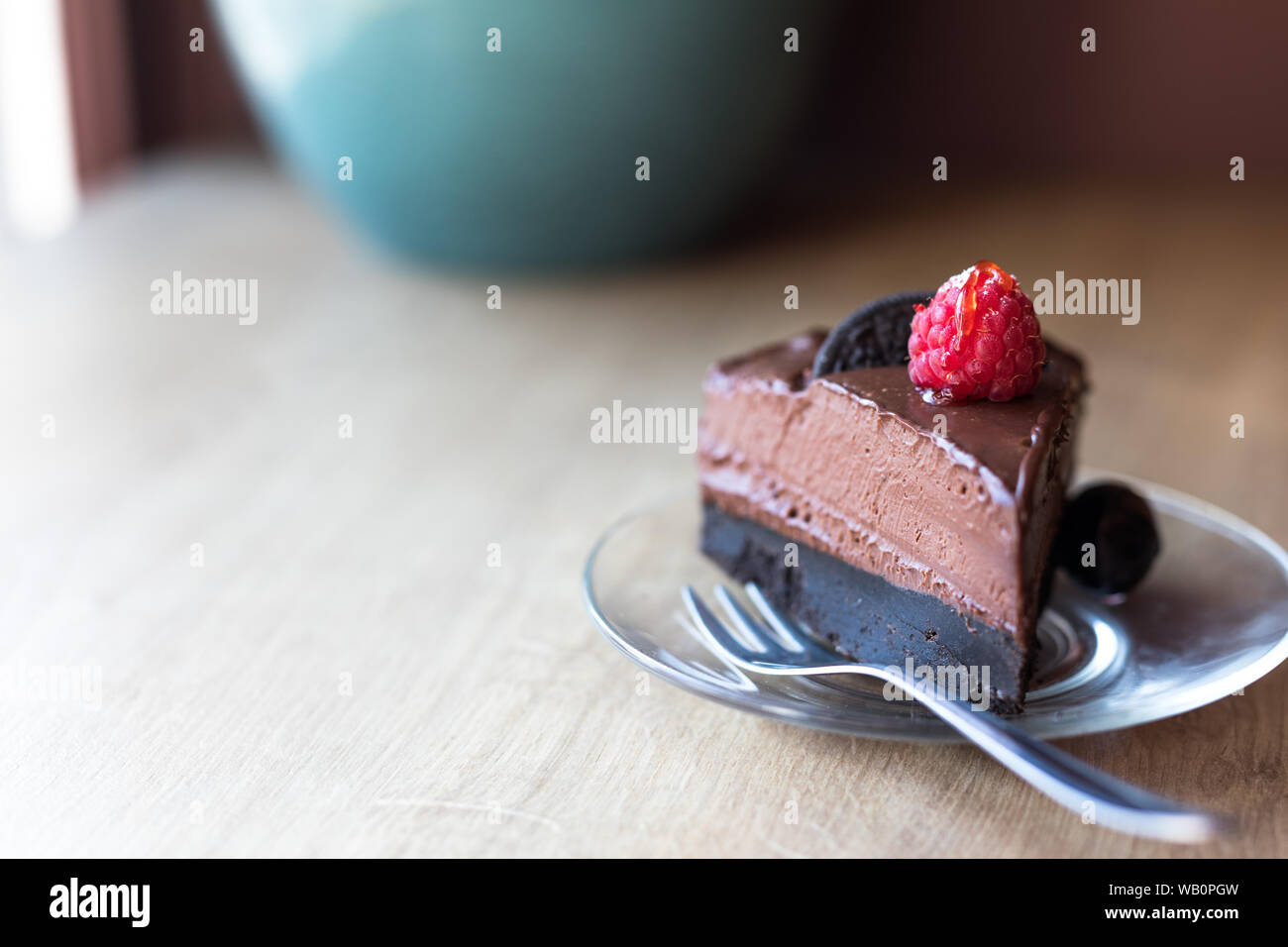 Ein Stück roher Avocado-Schokoladenkuchen mit einer hellen Himbeere und oreo-plätzchen oben. Stockfoto