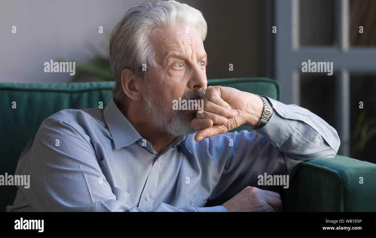 Nachdenklich nachdenklich älterer Mann weg suchen allein zu Hause sitzen Stockfoto
