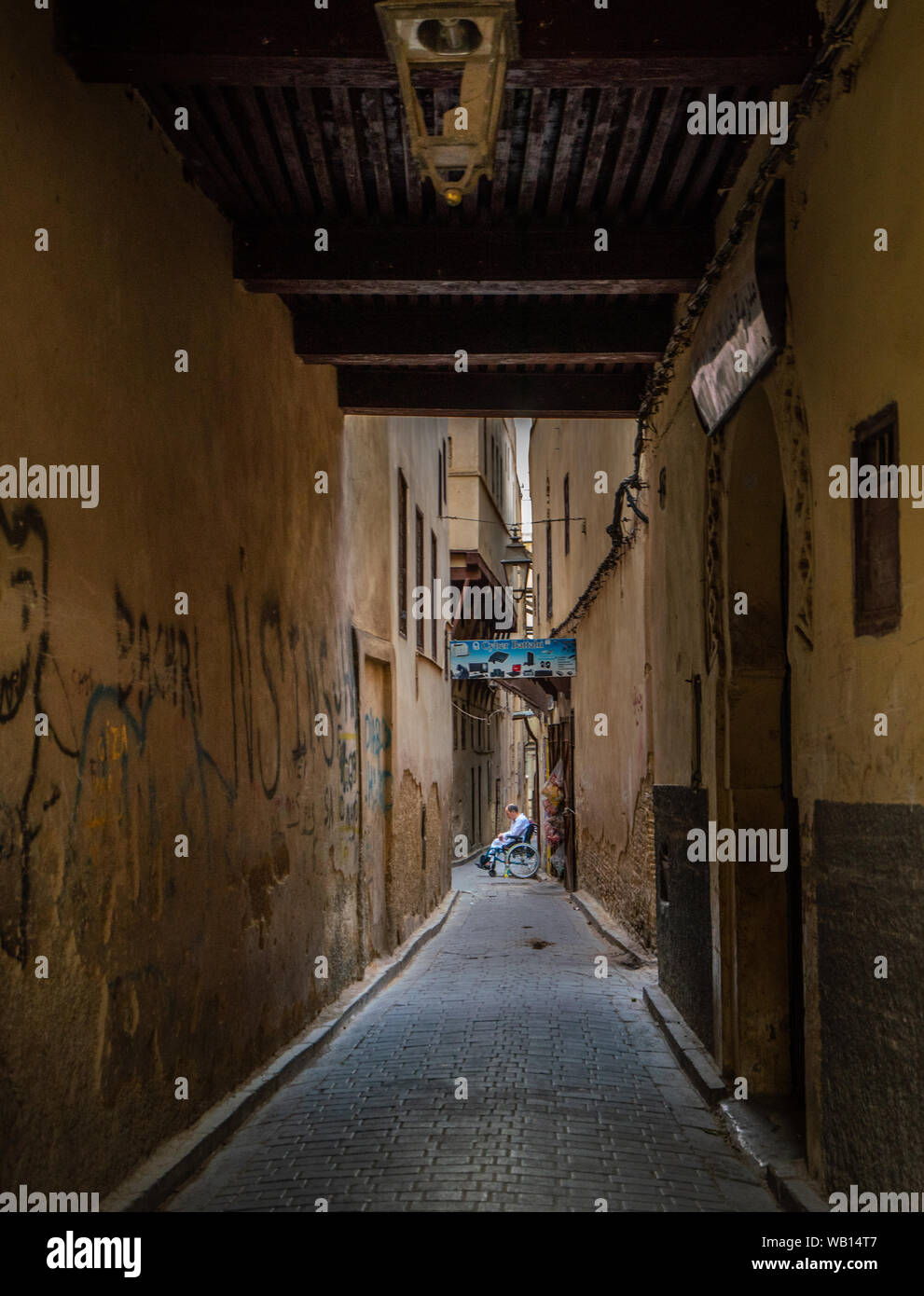 Behinderte Person in einem Rollstuhl in der schmalen Straße von Fes Stockfoto