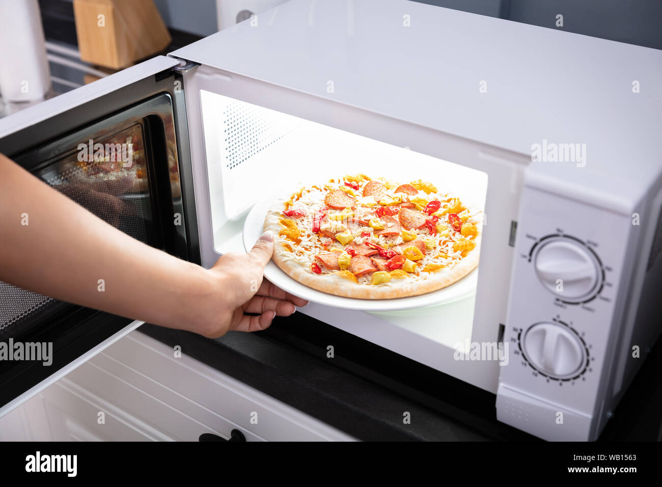 Close-up eine glückliche Frau backen Pizza in der Mikrowelle Stockfoto