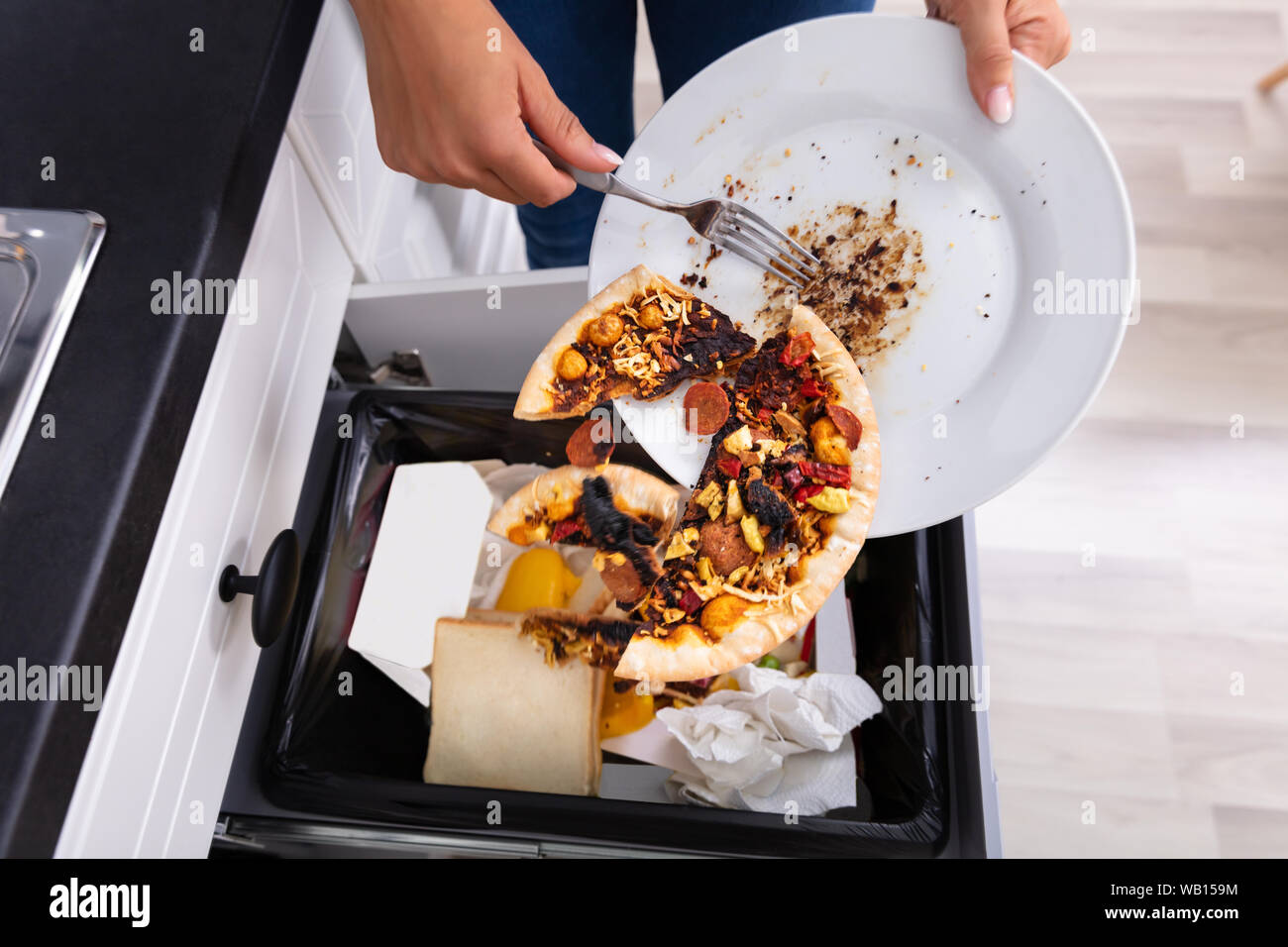Nahaufnahme einer Person werfen Pepperoni Pizza auf dem Teller in Mülleimer Stockfoto