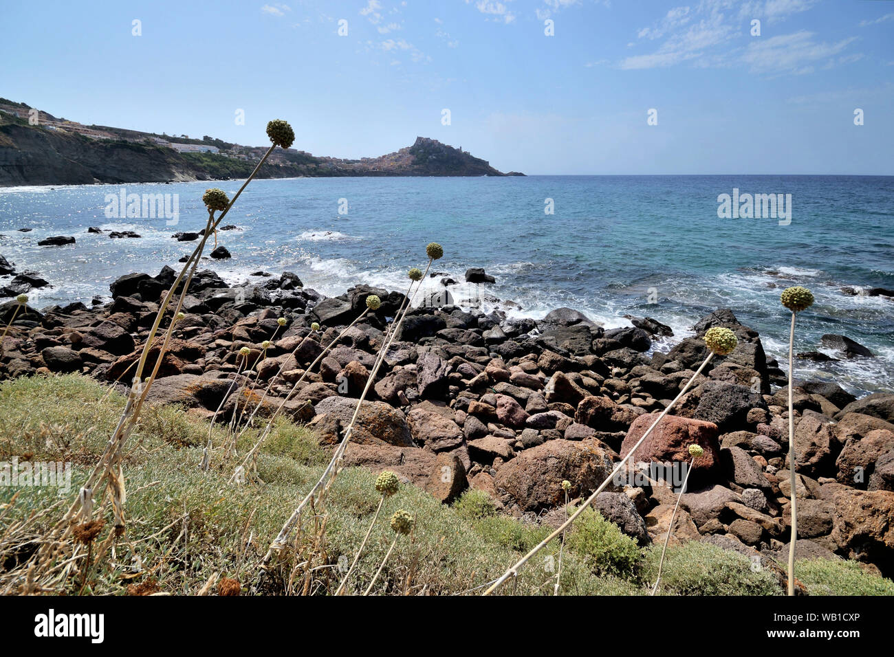 Die herrlichen Felsen Felsen der Cantareddi Strand im Norden von Sardinien an einem sonnigen Sommertag. Castelsardo Stadt auf einem Hügel im Hintergrund Stockfoto