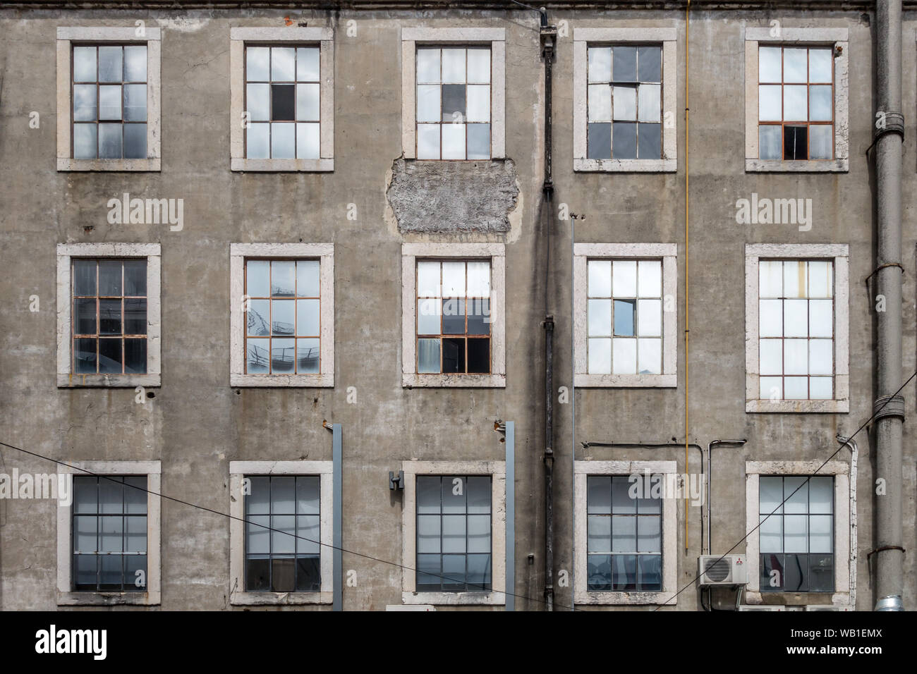 Nahaufnahme Landschaft detail Architektur Blick auf 3 Reihen von Fensterrahmen und Scheiben in verschlissenen Zustand in Beton wand Fassade der industriellen Gebäude in L Stockfoto