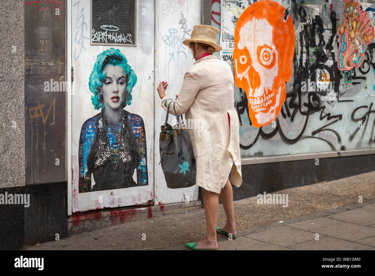 Seltsam gekleidete Dame stand vor der Marilyn Graffiti Stockfoto