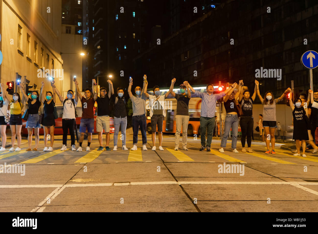 Hong Kong Demonstranten unterschiedlichen Alters halten Hände über der Straße, in einem belebten lokalen Wohngebiet Menschenkette für Demokratie zu bilden. Sie würden Rückzug auf dem Bürgersteig, wenn die Ampel für die Fußgänger läuft rot an der Ampel passieren zu lassen. Tausende von Hong Kong Demonstranten link Hände Menschenkette quer durch die Stadt zu bilden, für die Demokratie zu nennen. Die Ketten, die drei U-Routen, beliefen sich auf rund 40 Kilometer (25 Meilen) lang verfolgt. Die Demonstranten sagten, sie inspiriert waren, durch den "Baltischen Weg", wenn Millionen von Menschen eine Kette in drei Ländern (Estland, Lettland und Lithua Stockfoto