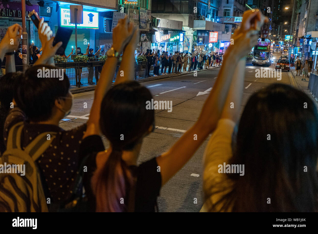 Hong Kong Demonstranten unterschiedlichen Alters halten Hände über der Straße, in einem belebten lokalen Wohngebiet Menschenkette für Demokratie zu bilden. Sie würden Rückzug auf dem Bürgersteig, wenn die Ampel für die Fußgänger läuft rot an der Ampel passieren zu lassen. Tausende von Hong Kong Demonstranten link Hände Menschenkette quer durch die Stadt zu bilden, für die Demokratie zu nennen. Die Ketten, die drei U-Routen, beliefen sich auf rund 40 Kilometer (25 Meilen) lang verfolgt. Die Demonstranten sagten, sie inspiriert waren, durch den "Baltischen Weg", wenn Millionen von Menschen eine Kette in drei Ländern (Estland, Lettland und Lithua Stockfoto