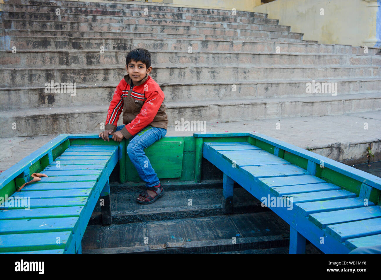 Indische armes Kind spielen rund um den blauen Boot Stockfoto
