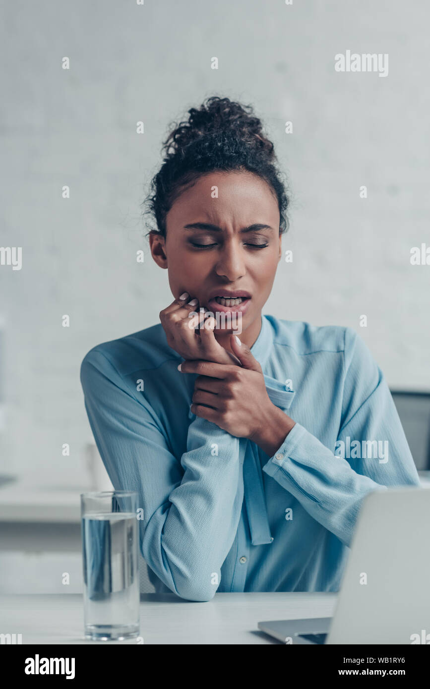 Ziemlich afrikanische amerikanische Geschäftsfrau Leiden von Zahn Schmerzen beim Sitzen am Arbeitsplatz Stockfoto
