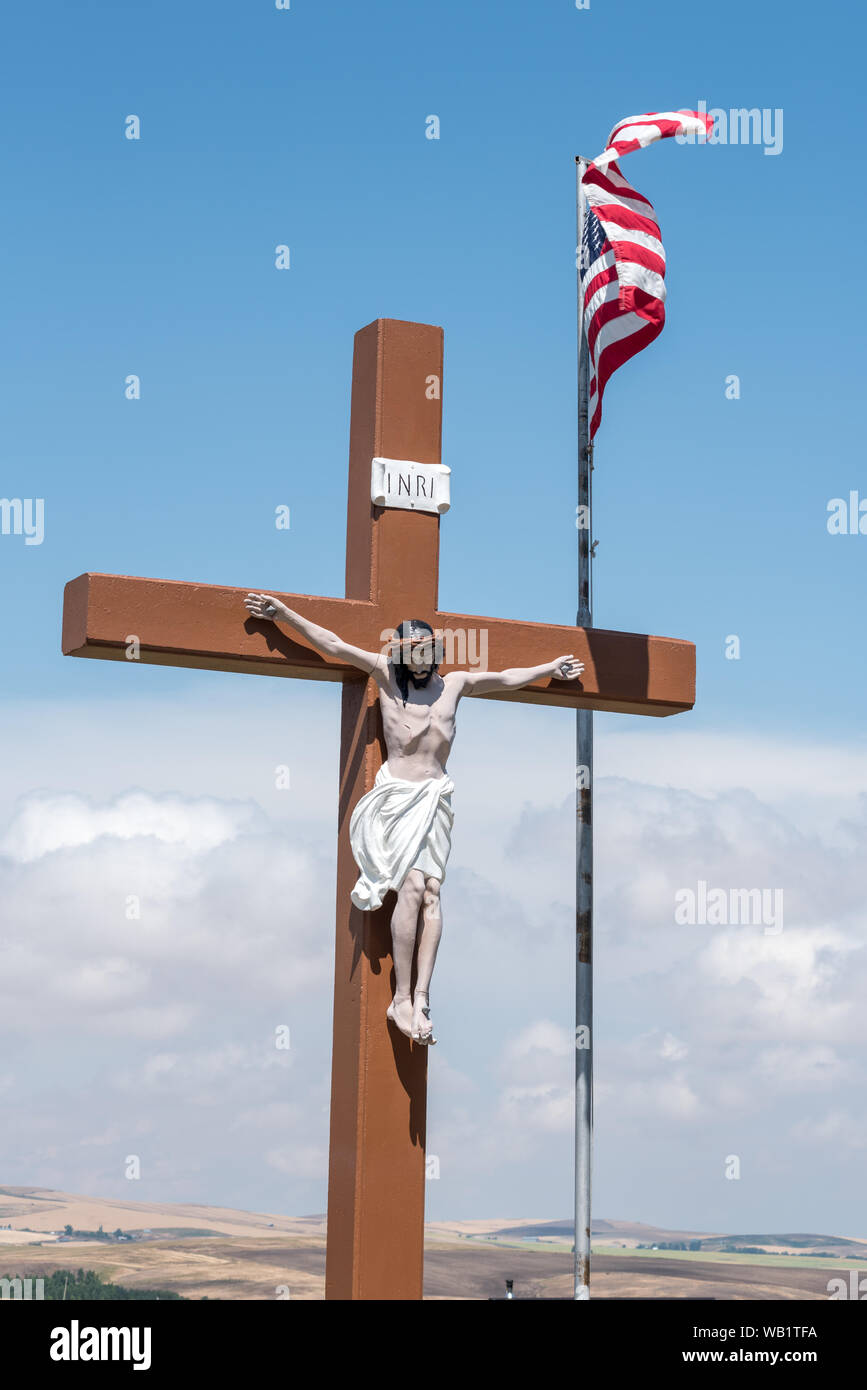 Jesus am Kreuz und die amerikanische Flagge in einem katholischen Friedhof in Cottonwood, Idaho. Stockfoto
