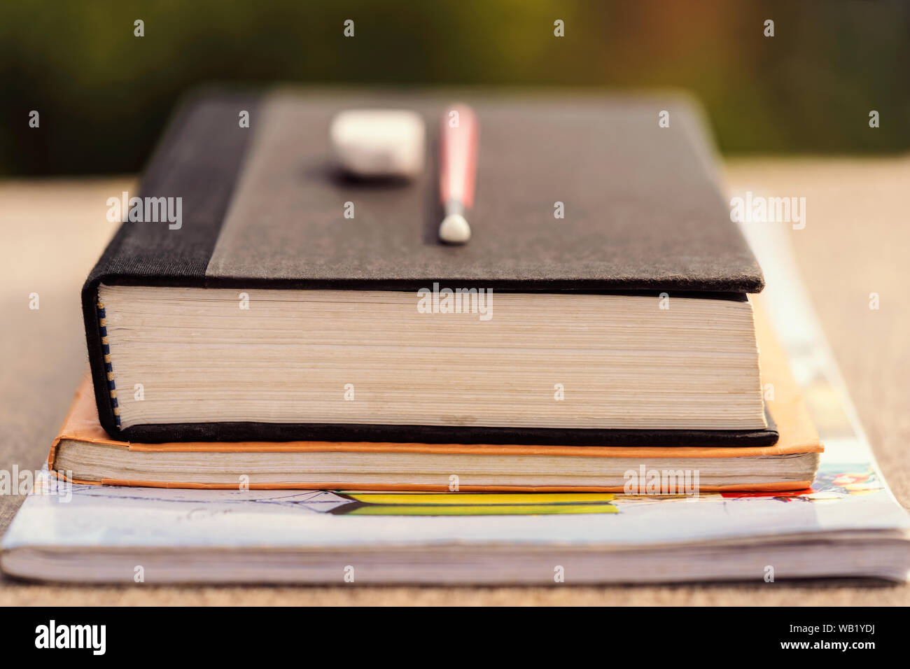 Einen Stapel Bücher & Notebooks mit Bleistift und Radiergummi auf einer hölzernen Schreibtisch bei outdoor Park. Hintergrund Konzept für Ausbildung Darlehen, Gelehrsamkeit, Lehrer Tag Stockfoto