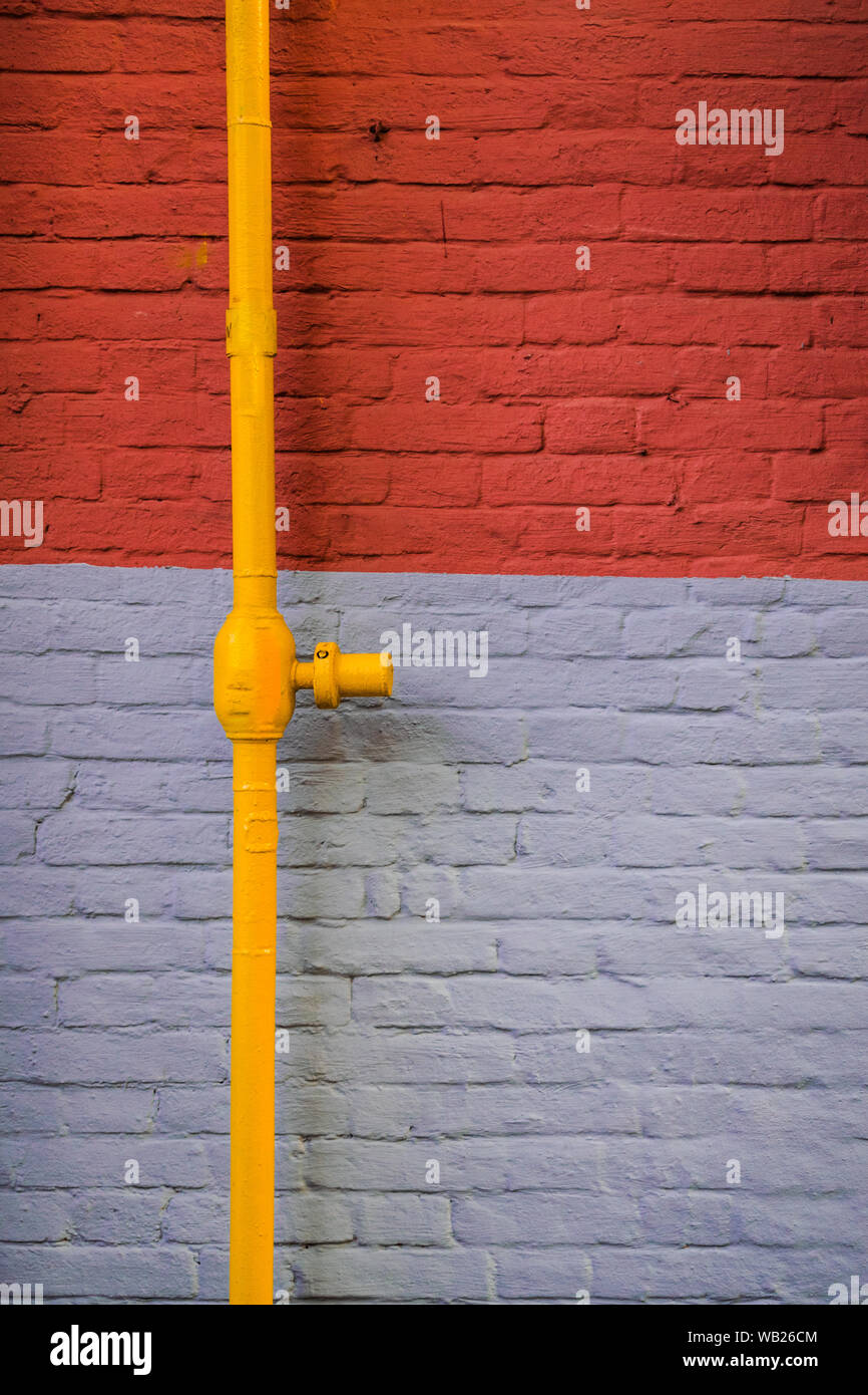 Grau und Orange brick wall mit gelb Rohr Stockfoto
