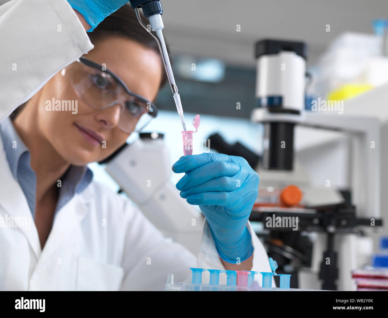 Die biotechnologische Forschung. Wissenschaftler pipettieren Samples in eine Mikro-zentrifugenröhrchen bereit für die automatisierte Analyse. Stockfoto