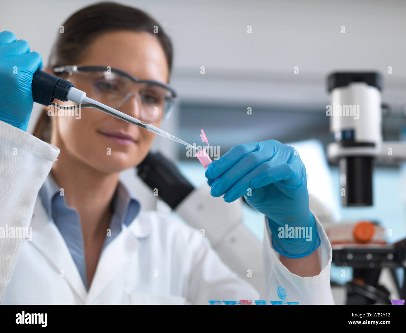 Die biotechnologische Forschung. Wissenschaftler pipettieren Samples in eine Mikro-zentrifugenröhrchen bereit für die automatisierte Analyse. Stockfoto