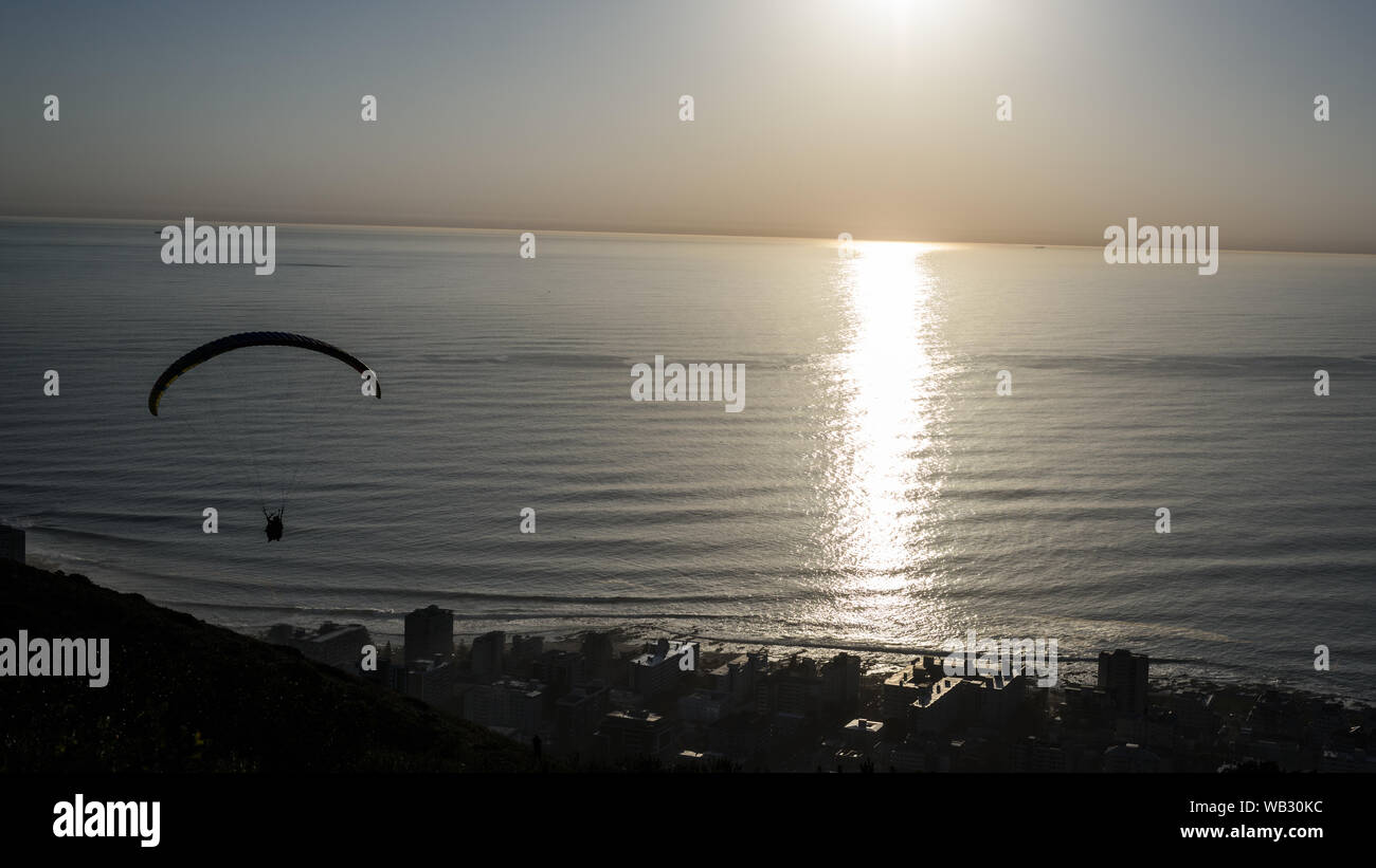 Ein Gleitschirm startet von Cape Town Signal Hill bei Sonnenuntergang über dem Seapoint Vorort auf der Südafrikanischen Atlantik Stockfoto