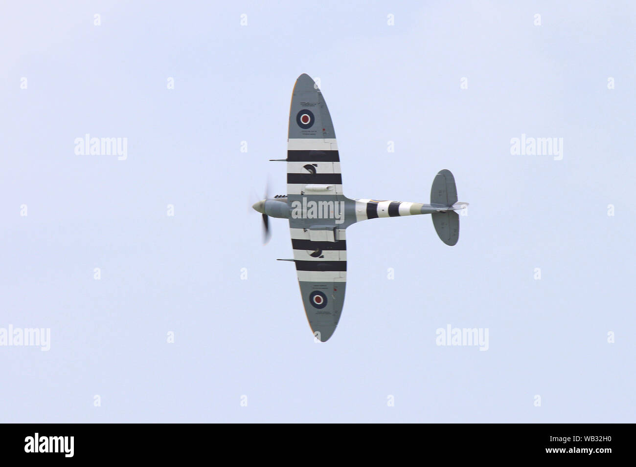 Eine Spitfire Pässe Overhead seine elliptische Flügel zeigen. Die Streifen waren auf alliierte Flugzeuge, um Sie von feindlichen Flugzeugen auf D zu unterscheiden - Tag setzen. Stockfoto