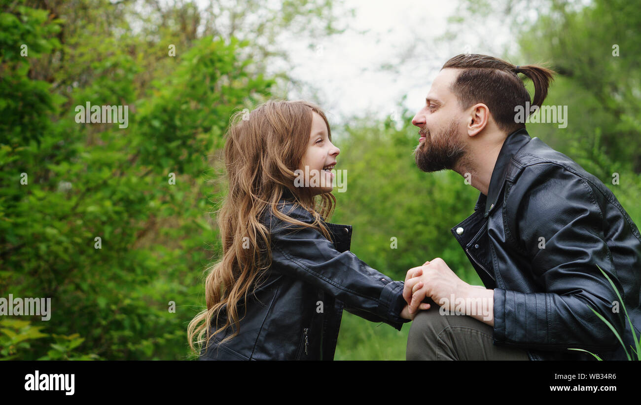 Modernes, stilvolles Familie Fuß in den Park. Süße kleine Tochter ruft Papa zu spielen. Zeit zusammen. Familie suchen. Urban casual Outfit. Vaterschaft ma Stockfoto