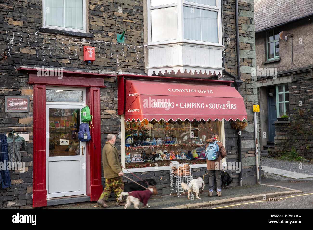 Paar ihre Hunde in der englischen Dorf Coniston im Lake District National Park an einem Wintertag, Cumbria, England Stockfoto