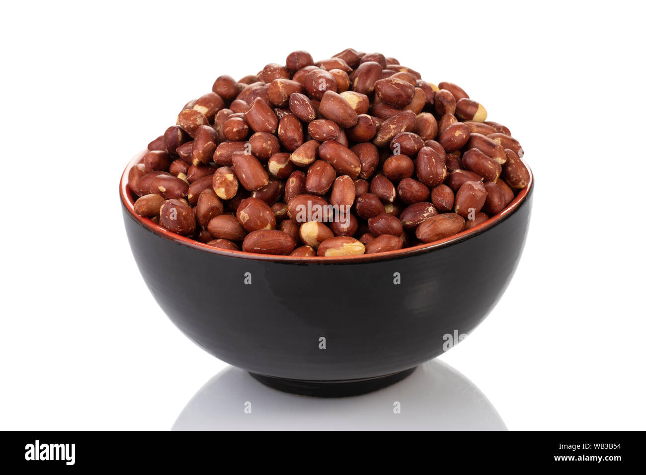 Eine schwarze Schüssel gefüllt mit rohen Erdnüssen auf weißem Hintergrund. Stockfoto