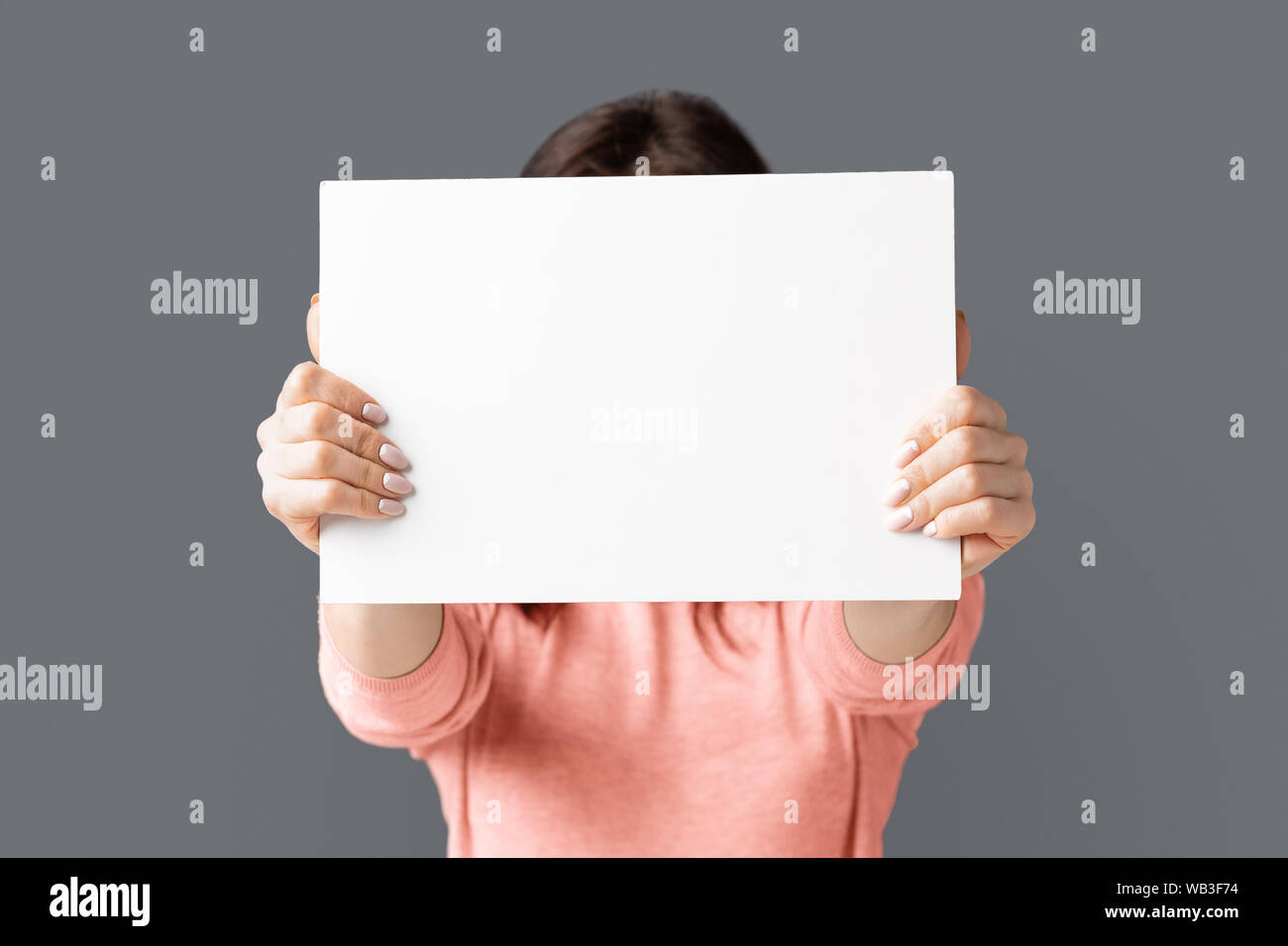 Frau mit leeren Werbetafel vor ihrem Gesicht Stockfoto