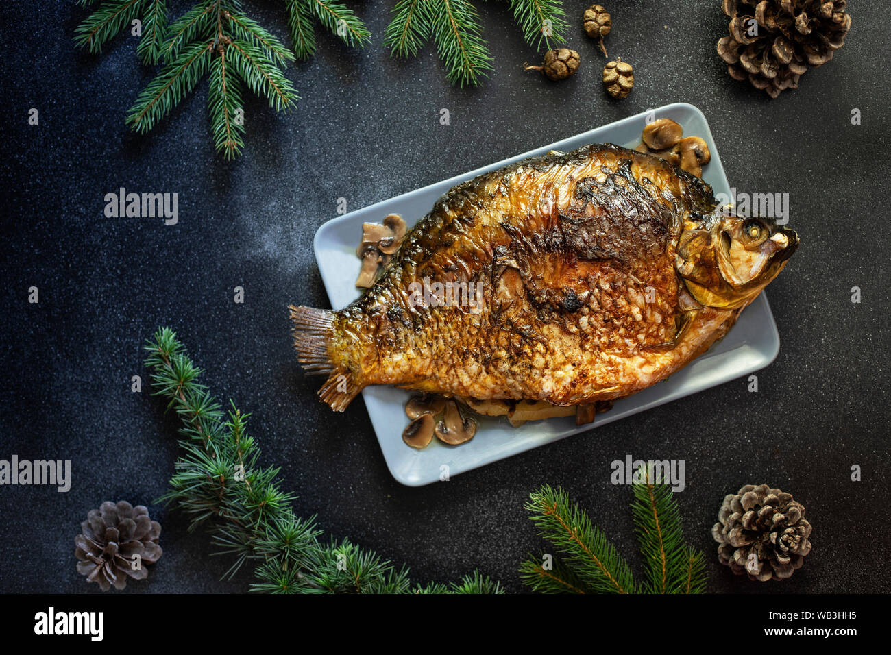 Weihnachten ganze gebackene Karpfen mit Pilzen. Auf einem dunklen Hintergrund serviert. Traditionelle Weihnachtsabend Mahlzeit. Ansicht von oben. Platz für Text Stockfoto