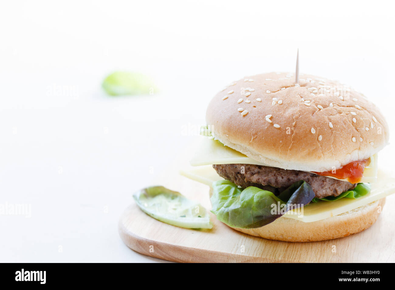 Burger mit Rindfleisch, frischer Salat und Käse auf Holzplatte, weißer Hintergrund Stockfoto