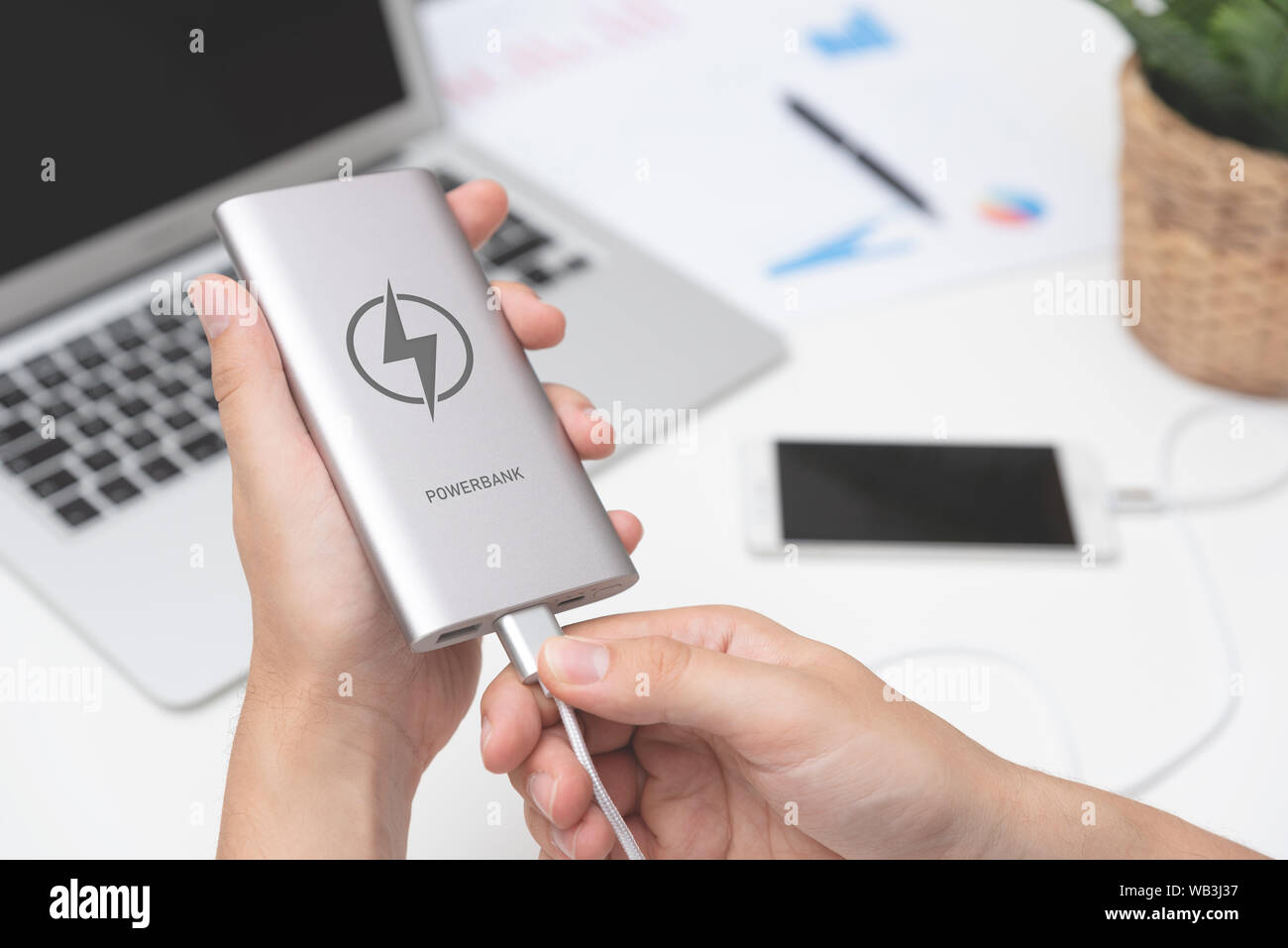 Mann Anschließen von USB-Ladegerät smart phone. Power Bank, Handy Akku auf Schreibtisch Konzept Stockfoto