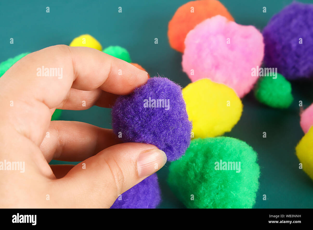 Hand berührt eine weiche Wolle pompom. Das Konzept der Touch, Taktilität, Gefühle. Stockfoto