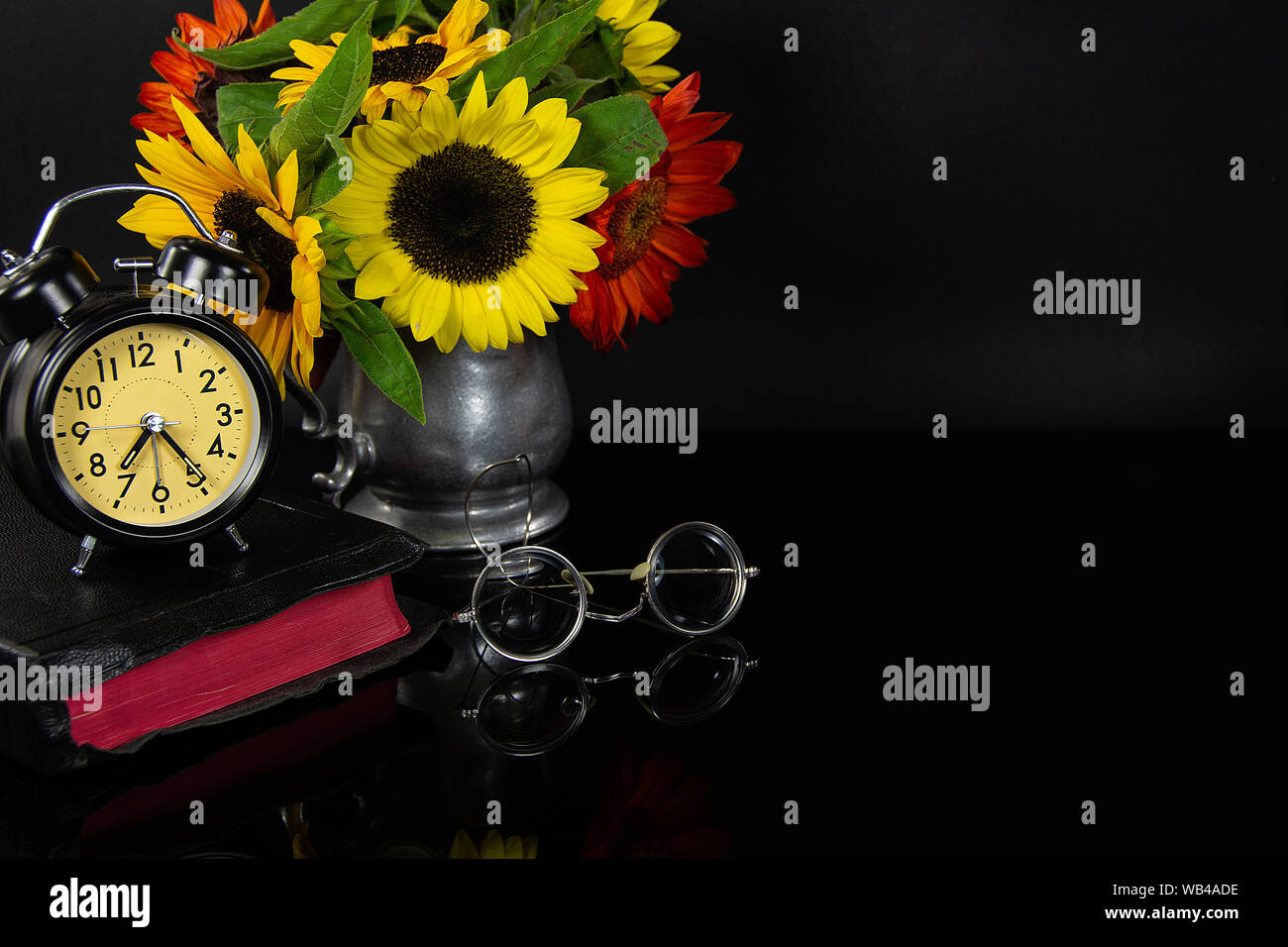 Sonnenblume Strauß in vintage Zinnkrug mit Bibel und alte Brillen auf schwarz Reflexion Stockfoto